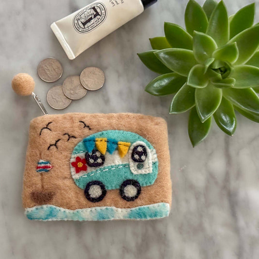 Felt coin purse with camper design on a marble surface with coins and a plant.