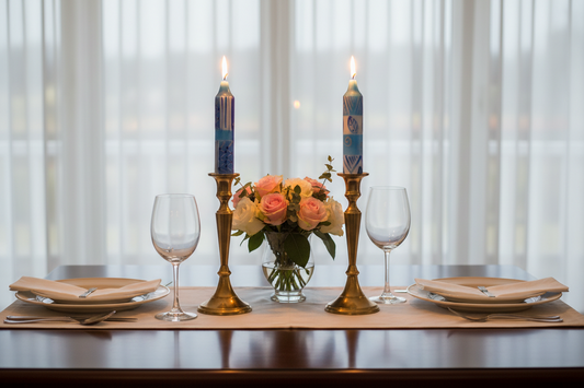 Dining table set with 4" blue and white Shabbat candles, flowers, and glasses on a wooden table.