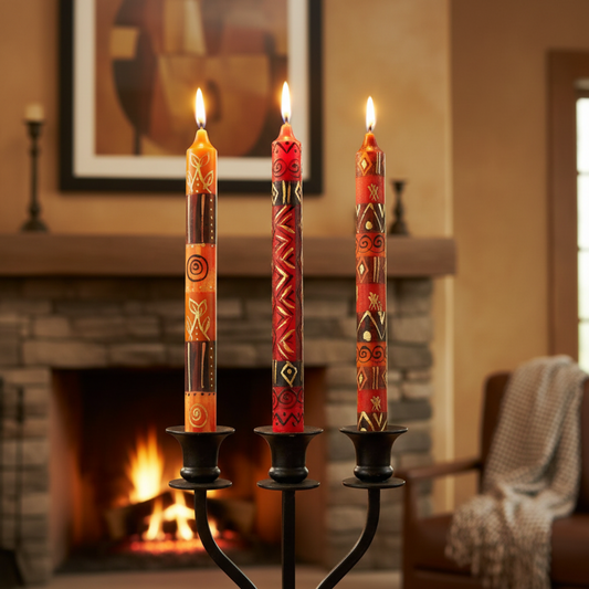 Three lit candles with decorative patterns on a black candle holder in front of a fireplace.