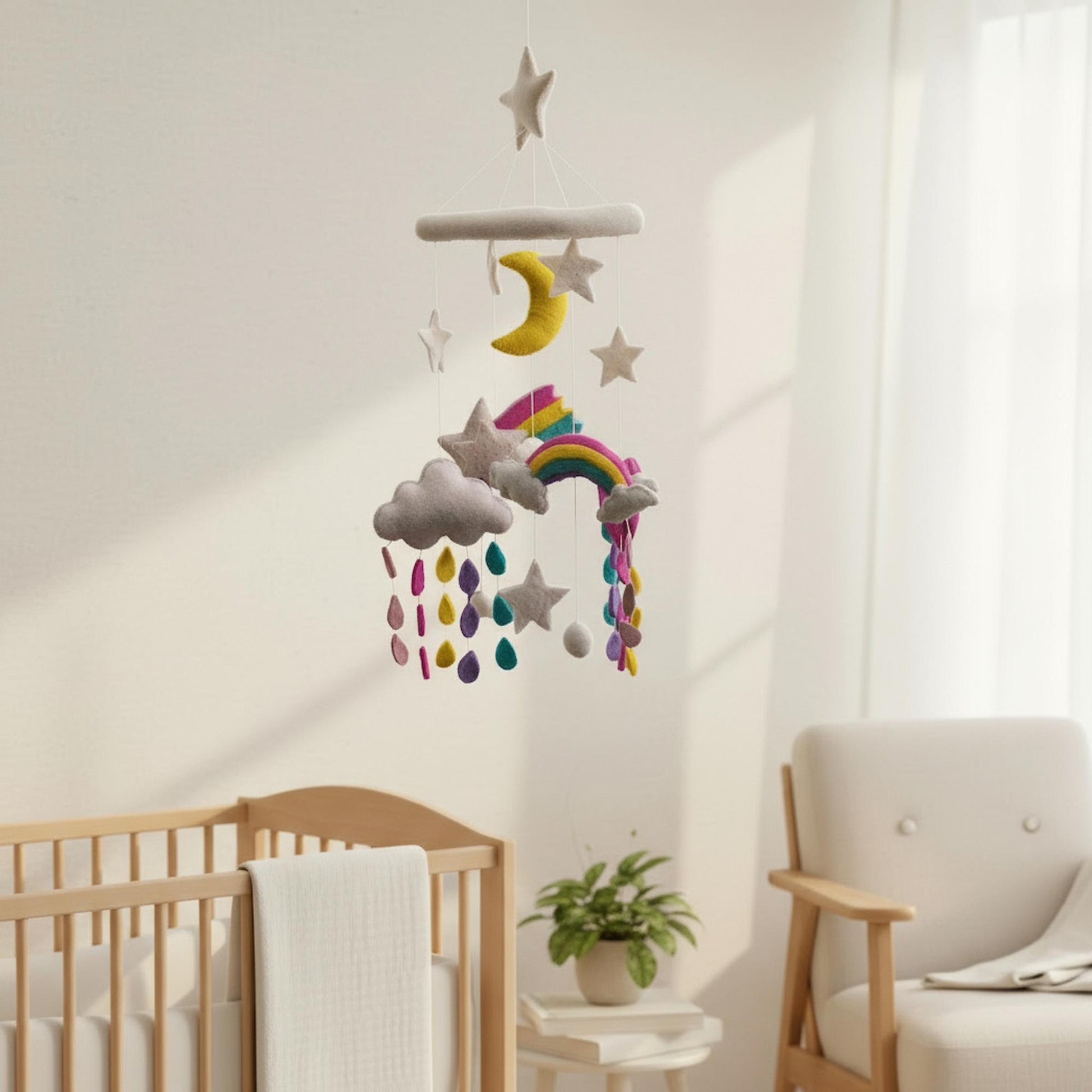 Children's room with a crib, chair, and colorful, rainbow felt mobile hanging above.