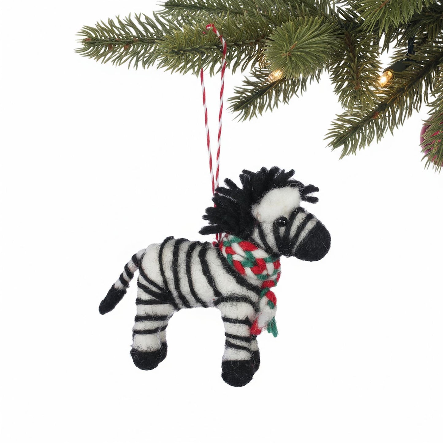 Zebra ornament with a colorful scarf hanging from a Christmas tree.